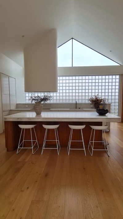 Kitchen with a sculptural rangehood under a raked ceiling